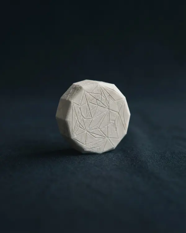 Peça comemorativa impressa em 3D com padrão geométrico gravado na superfície